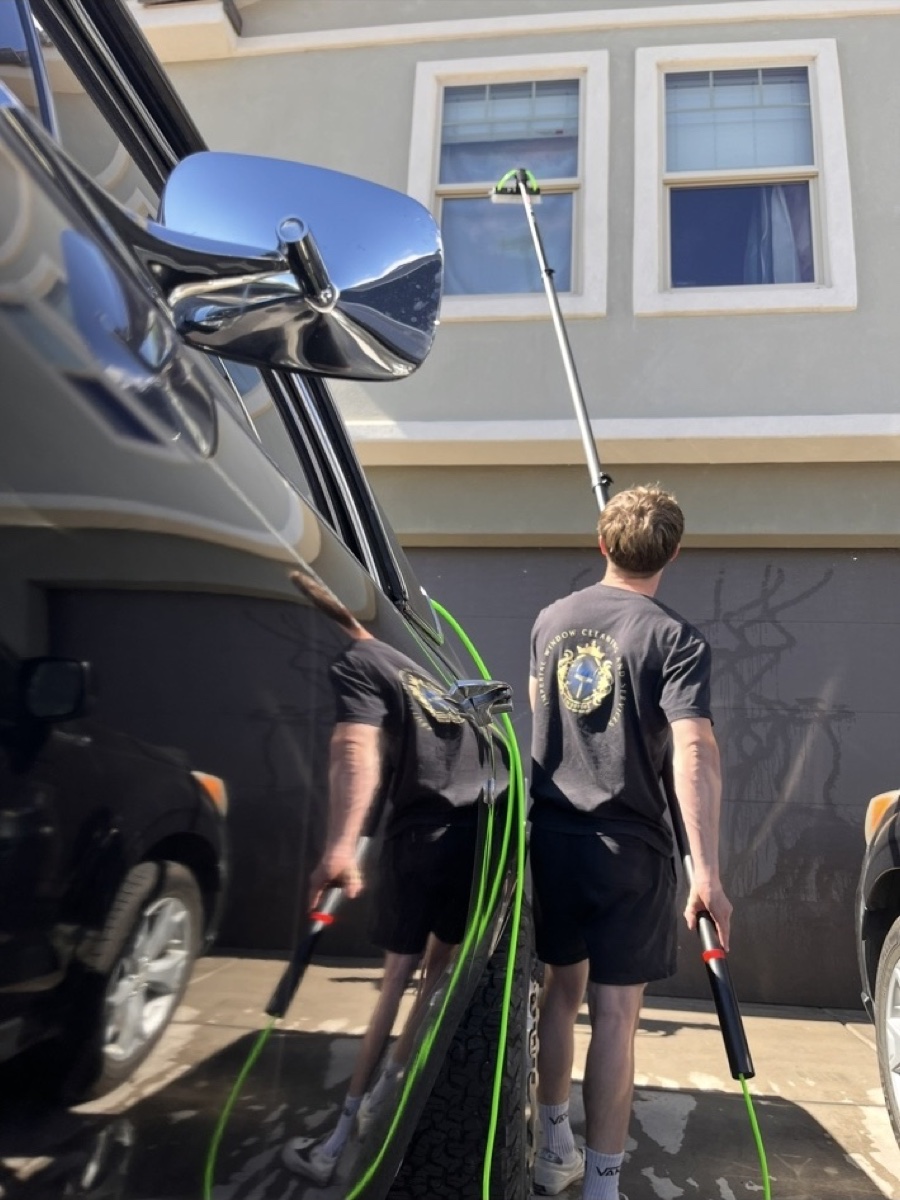 Imperial crew member cleaning home windows with a water-fed pole