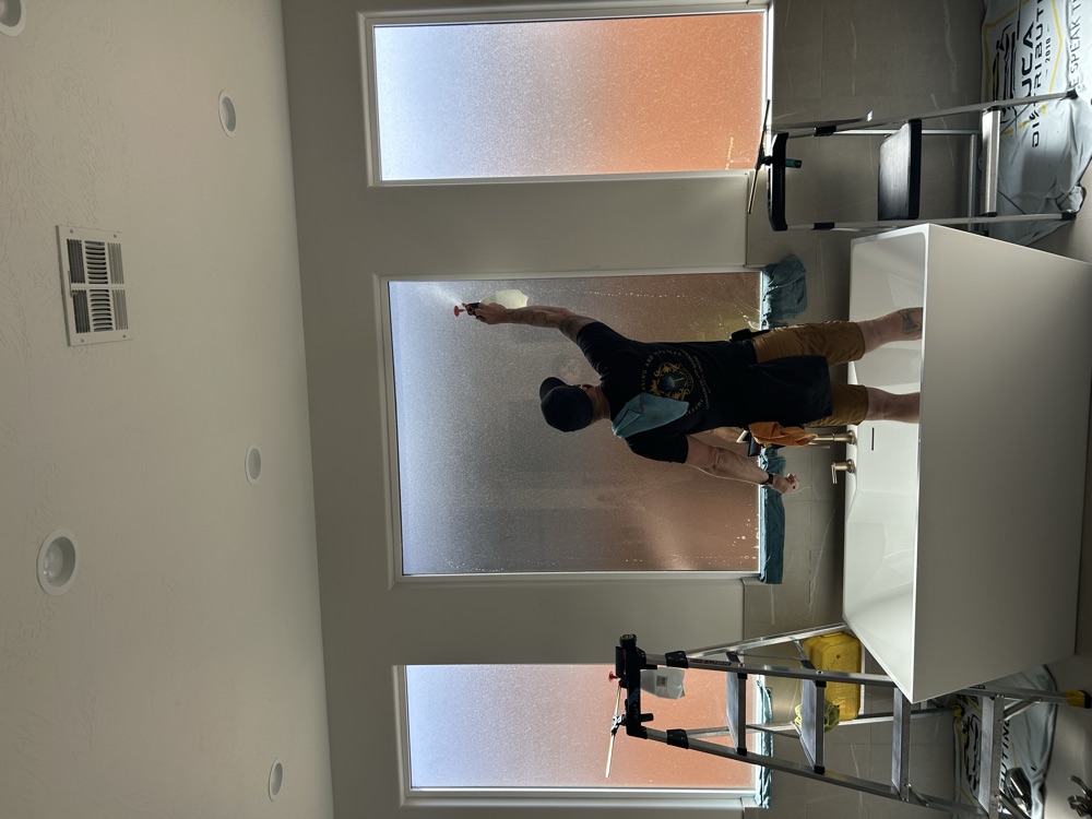 Installer applying frosted privacy film to tall windows