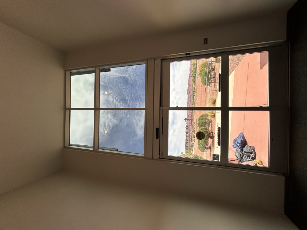 Two-story window wall with tint and a red-rock view